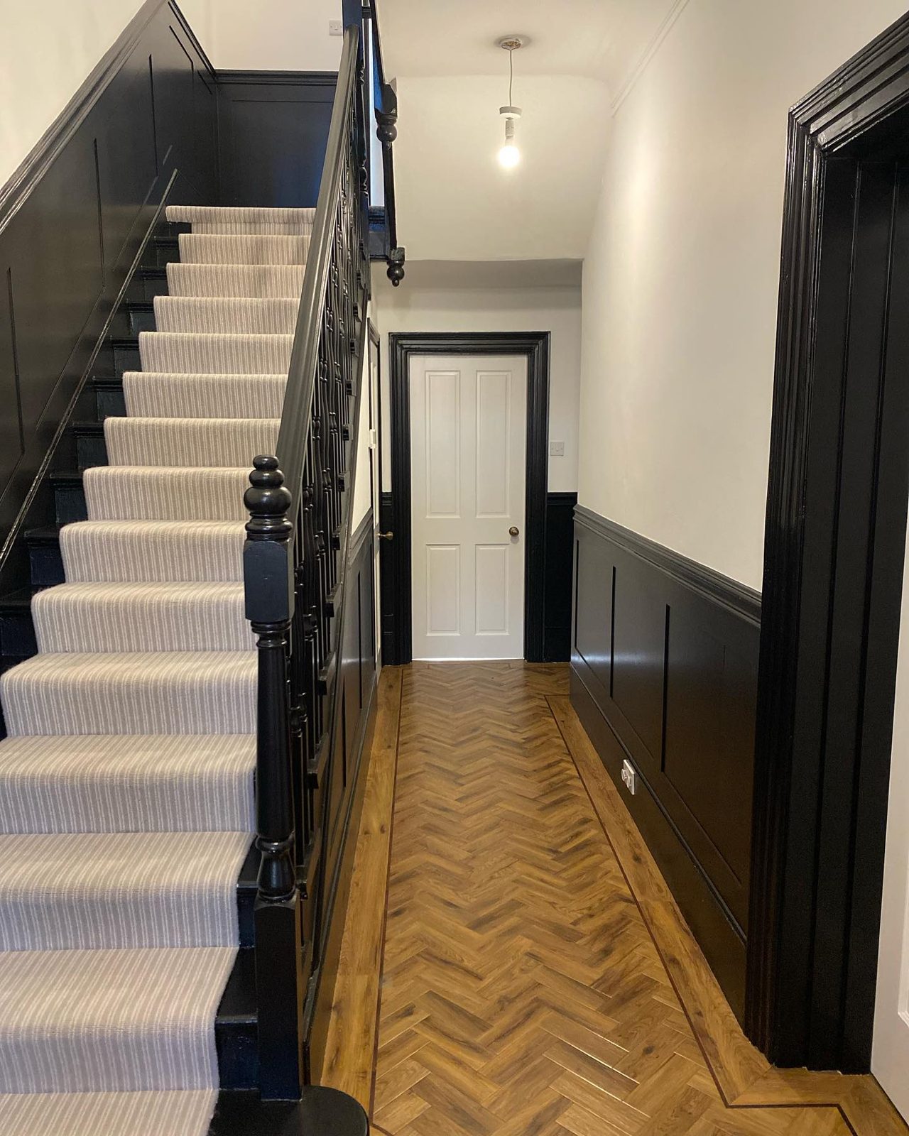 Hallway and staircase decorated in black and white with dark panelling, Eastbourne